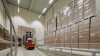 Almacén con estanterías altas y pasillos iluminados por regletas LED, proporcionando una luz clara y uniforme para un ambiente de trabajo seguro y eficiente