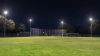 Vista nocturna de un campo de fútbol brillantemente iluminado por múltiples proyectores LED exteriores, demostrando su amplia cobertura.