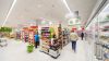 Pasillo bien iluminado de un supermercado, mostrando estantes llenos de productos y clientes comprando, destacando la correcta iluminación LED